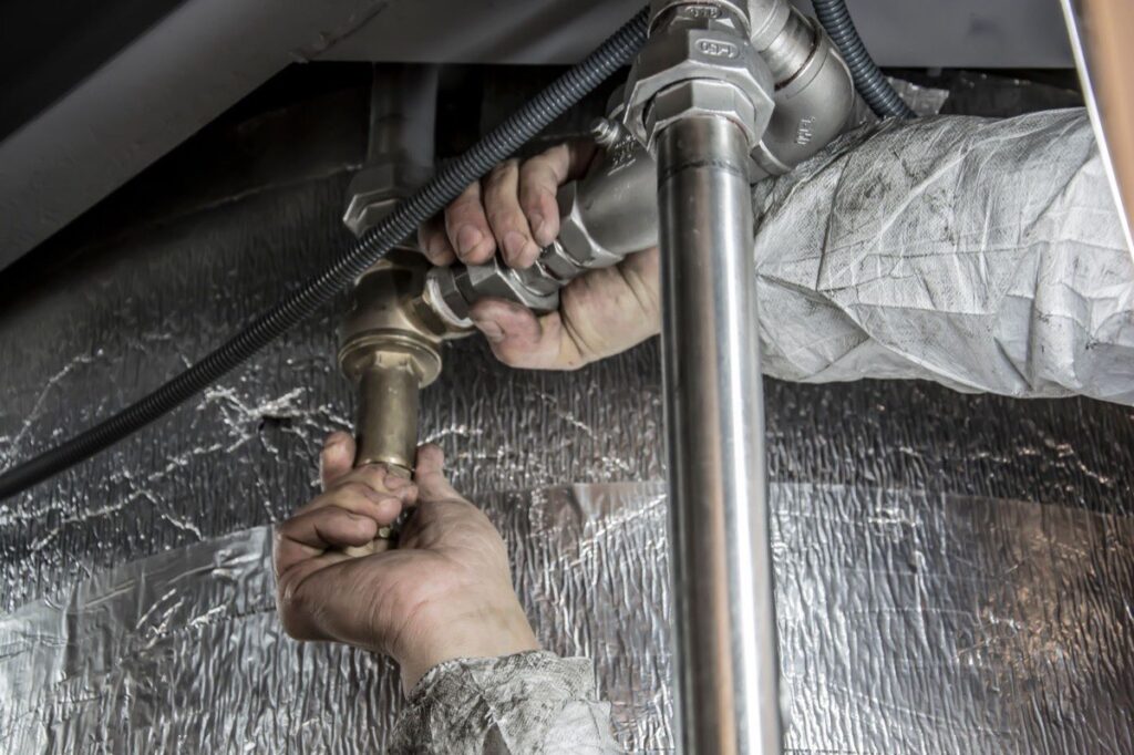 Plumber tightening pipe fittings during a whole-house repipe
